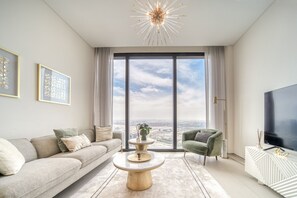 A modern living room with a large window, a sofa, a coffee table, and a TV.