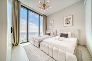 Ein modernes Hotelzimmer mit zwei Betten, großen Fenstern und Blick auf die Stadt.