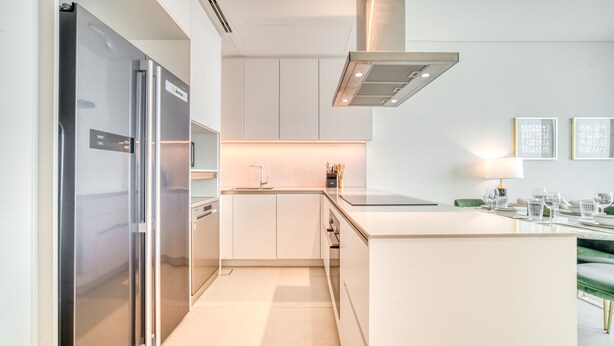 Una cocina moderna con electrodomésticos de acero inoxidable, armarios blancos y una isla central.