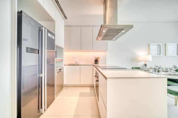 A modern kitchen with stainless steel appliances, white cabinetry, and a central island.
