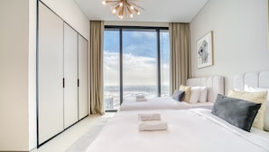 Una habitación de hotel moderna con una cama grande, vistas a la ciudad y un armario.
