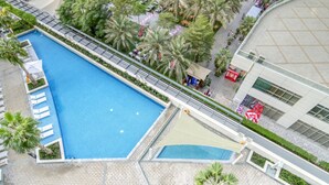 An aerial view of a hotel with a large swimming pool, palm trees, and a modern building with large windows. - Cityscape and Majestic Retreat at Address JBR (Dubai)