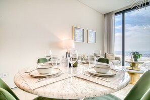 Ein Essbereich mit einem runden Tisch für vier Personen, Blick auf die Stadt durch große Fenster und einem modernen Interieur.