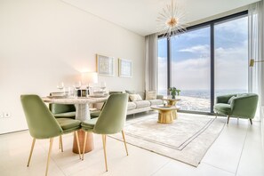 A modern living room with a dining area, large windows, and a view of the city.