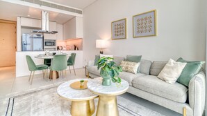 A modern living room with a sofa, two round tables, a dining area with chairs, and a kitchen in the background. - Cityscape and Majestic Retreat at Address JBR (Dubai)