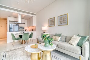 A modern living room with a sofa, two round tables, a dining area with chairs, and a kitchen in the background. - Cityscape and Majestic Retreat at Address JBR (Dubai)