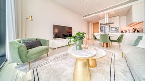 A modern living room with a green sofa, a round coffee table, and a flat-screen TV. - Cityscape and Majestic Retreat at Address JBR (Dubai)