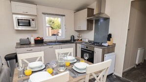 A modern kitchen with a dining area, equipped with a microwave, stove, oven, and sink. - Foxglove Lodge (Saltburn-by-the-Sea)