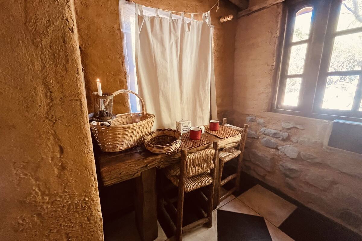 Cuina rústica amb taula de fusta, cistos de vimet i una espelma.