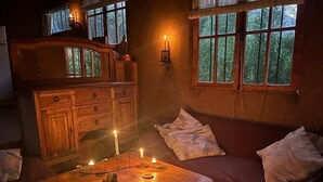 Una habitación acogedora con una mesa de madera, velas, un sofá y una ventana con vistas a árboles.