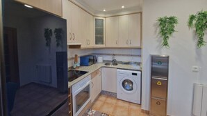 Uma cozinha compacta com máquina de lavar, micro-ondas e frigorífico.