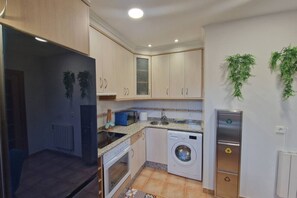 Une cuisine compacte équipée d’un lave-linge, d’un four à micro-ondes et d’un réfrigérateur.