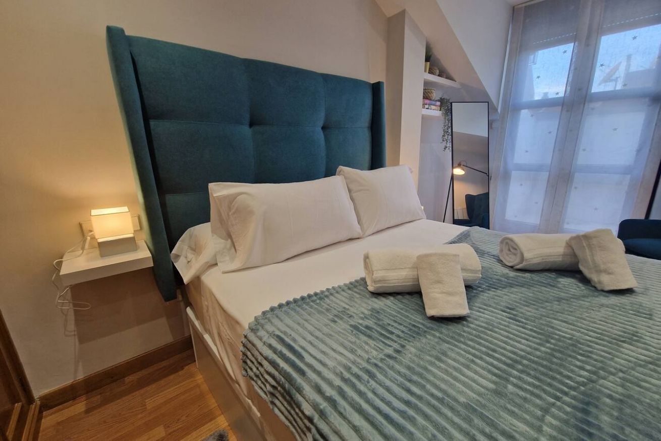 Een hotelkamer met een groot bed, een nachtkastje, een raam met uitzicht en een spiegel aan de muur.