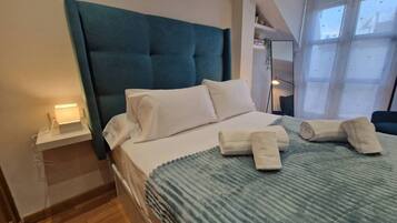 Een hotelkamer met een groot bed, een nachtkastje, een raam met uitzicht en een spiegel aan de muur.
