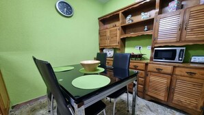Un coin repas comprenant une table, des chaises, une horloge, des meubles en bois et un four à micro-ondes.
