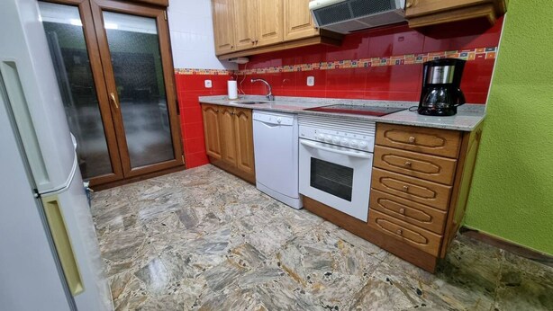 Une cuisine avec des meubles en bois, un lave-vaisselle blanc, une cuisinière et une machine à café.