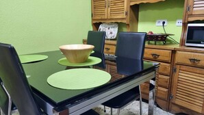 Un coin repas avec une table verte, des chaises noires et des meubles en bois.