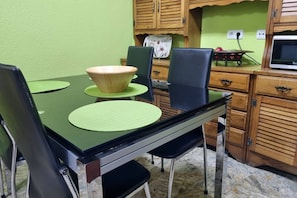 A dining area with a green table, black chairs, and wooden cabinets. - 126B Apto Playa - 3 Bedrooms by R2R Consulting (Gijón)