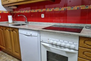 A kitchen with a dishwasher, stove, and wooden cabinets.