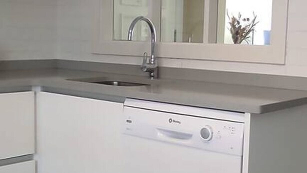 Una cocina con lavavajillas incorporado, un lavaplatos y una ventana sobre el lavaplatos.