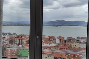 Blick aus einem Fenster auf eine Stadtansicht mit Gebäuden und einem Wasserabschnitt.