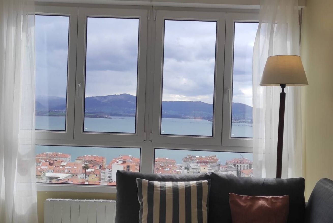 A room with a view of a body of water and buildings, a radiator, and a lamp.