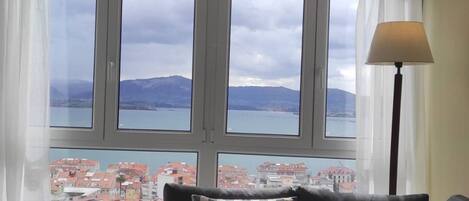 A room with a view of a body of water and buildings, a radiator, and a lamp.