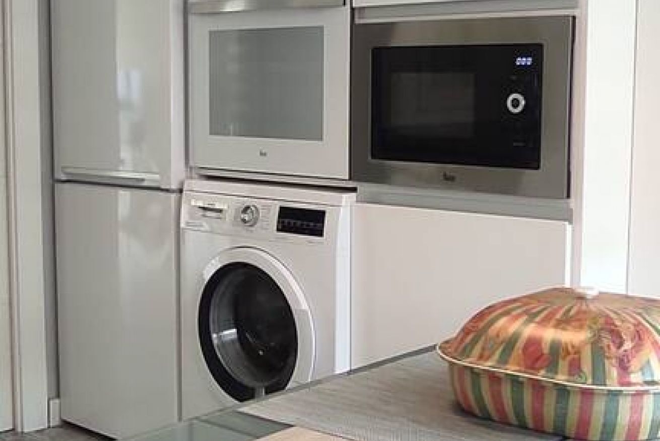 A kitchen with a microwave, oven, and washing machine.
