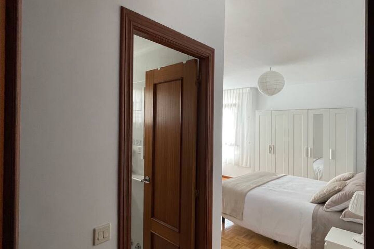 A bedroom with a bed, a wardrobe, and a mirror.