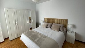 Een slaapkamer met een bed, nachtkastjes, een kledingkast en een hanglamp.