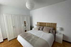 Ett sovrum med en säng, sängbord, en garderob och en hängande lampa.
