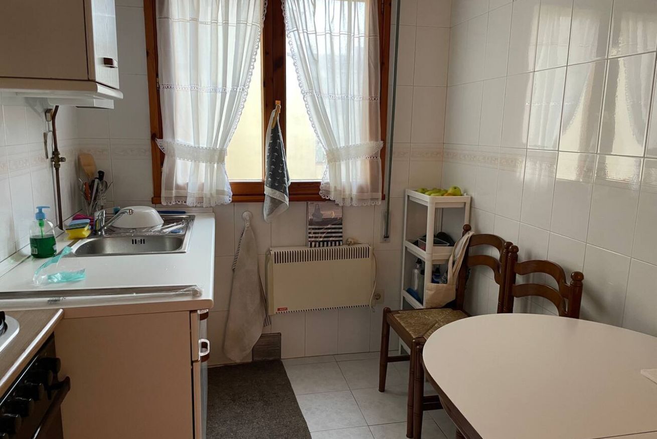 A kitchen with a sink, stove, and dining table.