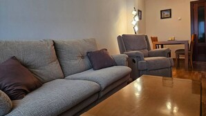 A living room with a sofa, armchairs, a coffee table, and a dining table with chairs.