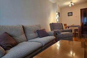A living room with a sofa, armchairs, a coffee table, and a dining table with chairs. - 22A02 Modern Apartment in Arriondas by R2R Consulting (Arriondas)