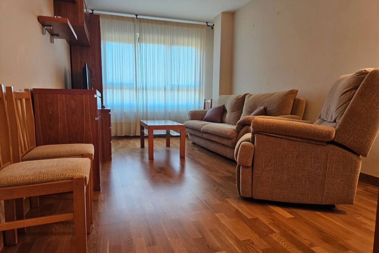 Een woonkamer met een bank, twee stoelen, een salontafel en een televisie.