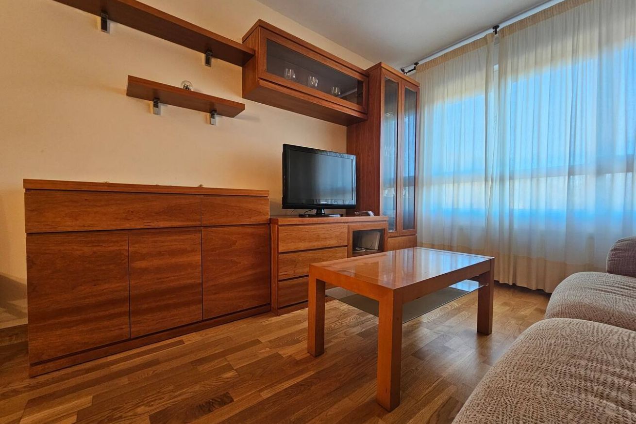 Un salon avec un meuble en bois, un téléviseur et une table.