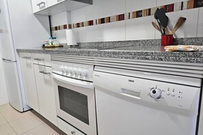 A kitchen with white cabinets, a granite countertop, a built-in oven, and a Zanussi dishwasher.