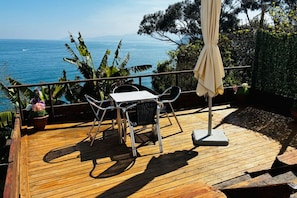 A wooden deck with a table and chairs, overlooking a body of water.
