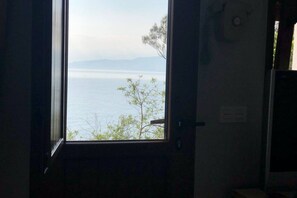 Una habitación con ventana que ofrece vista a un cuerpo de agua y montañas distantes.