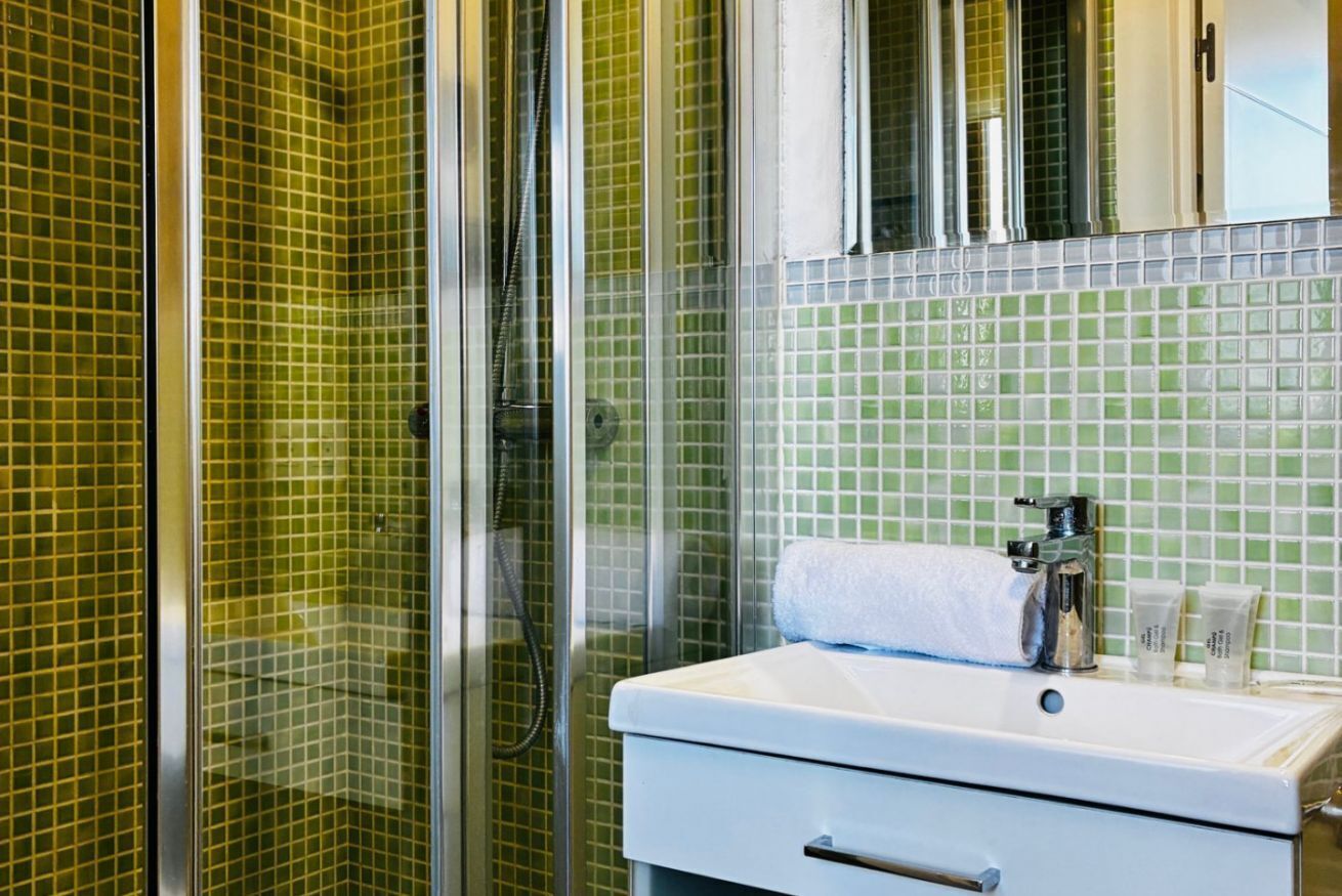 A bathroom with a shower, a sink, and a mirror.