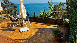 Um deck de madeira com móveis de exterior, uma mesa e cadeiras, com vista para um corpo de água.