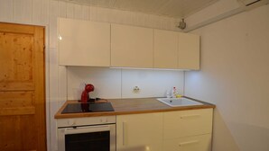 Una cocina compacta con armarios blancos, encimera de madera, horno integrado y un lavabo.