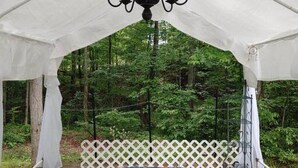 A covered outdoor area with a floral tablecloth, a hanging light fixture, and a white lattice fence. - RV Spot #3 at Watts Bar Lake (Spring City)