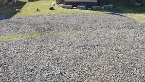 A small wooden cabin with a metal roof, surrounded by a gravel driveway and sparse grass. - RV Spot #3 at Watts Bar Lake (Spring City)