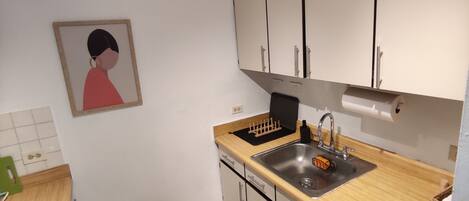A modern kitchen with white cabinets, a wooden countertop, a stainless steel sink, and a gas stove.
