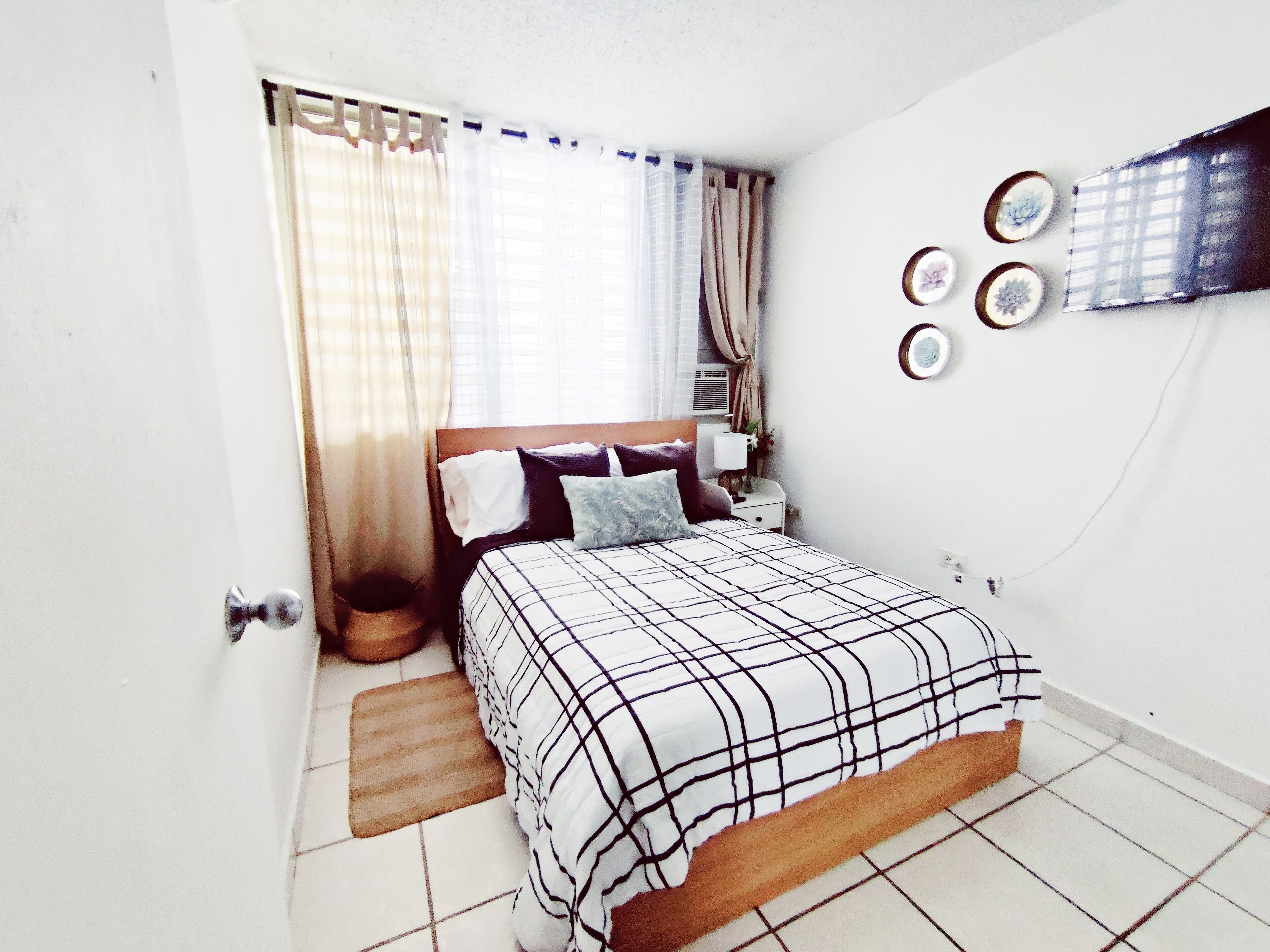 Ein Schlafzimmer mit Bett, Vorhängen, Nachttisch und Wandgestaltung.