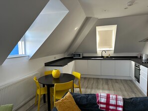 Een moderne keuken met witte kasten, een zwart aanrecht en een raam boven de spoelbak.