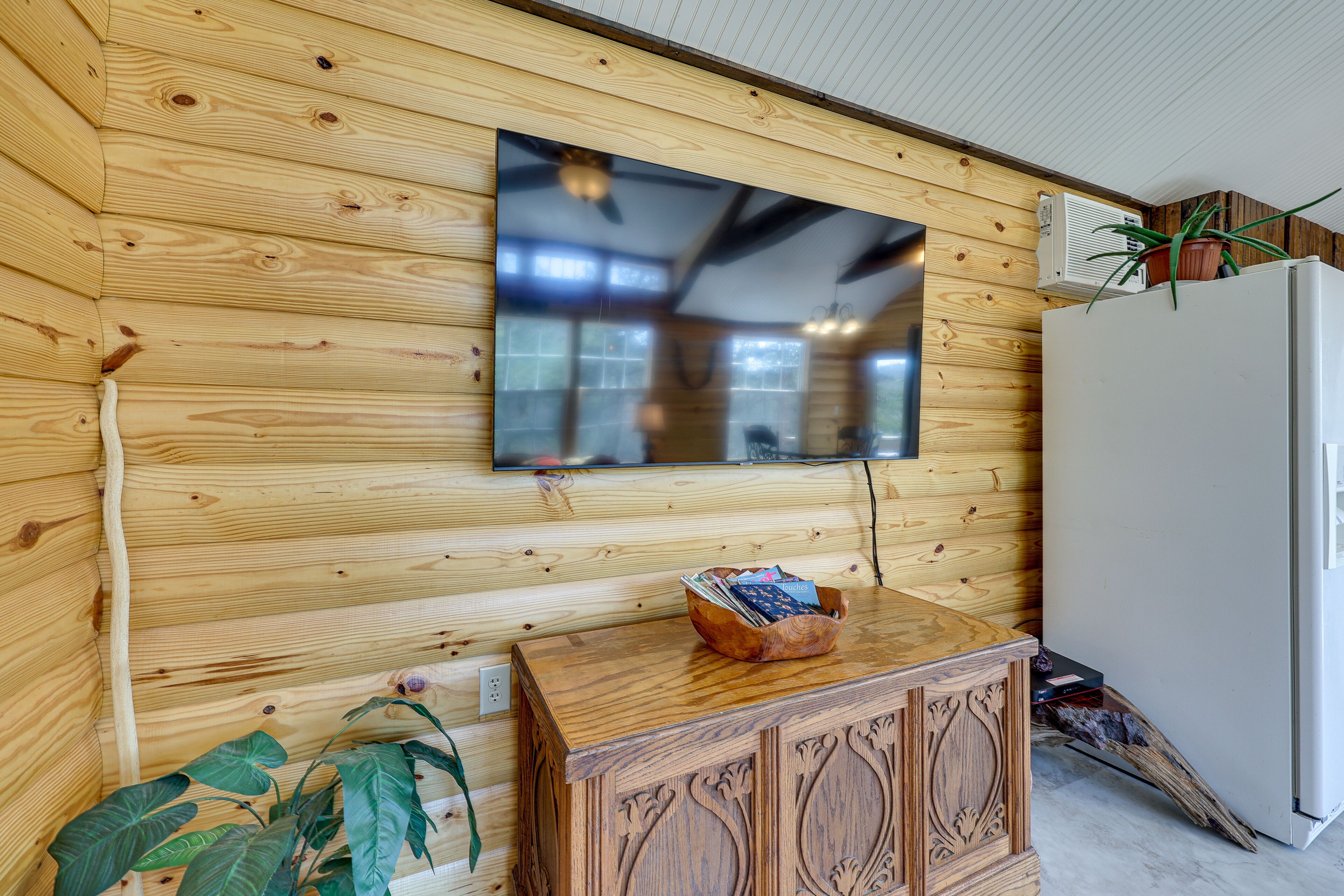 A wooden-paneled wall with a flat-screen TV mounted above a wooden cabinet.