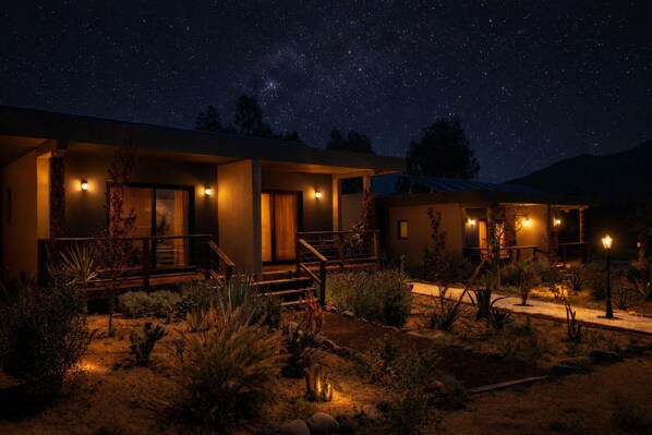 A modern hotel with a desert garden, illuminated windows, and a starry night sky. - Coquenas del Valle (Valle de Guadalupe)