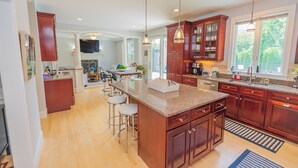 Una cocina amplia con armarios de madera, encimera de granito y una isla grande con taburetes de bar.
